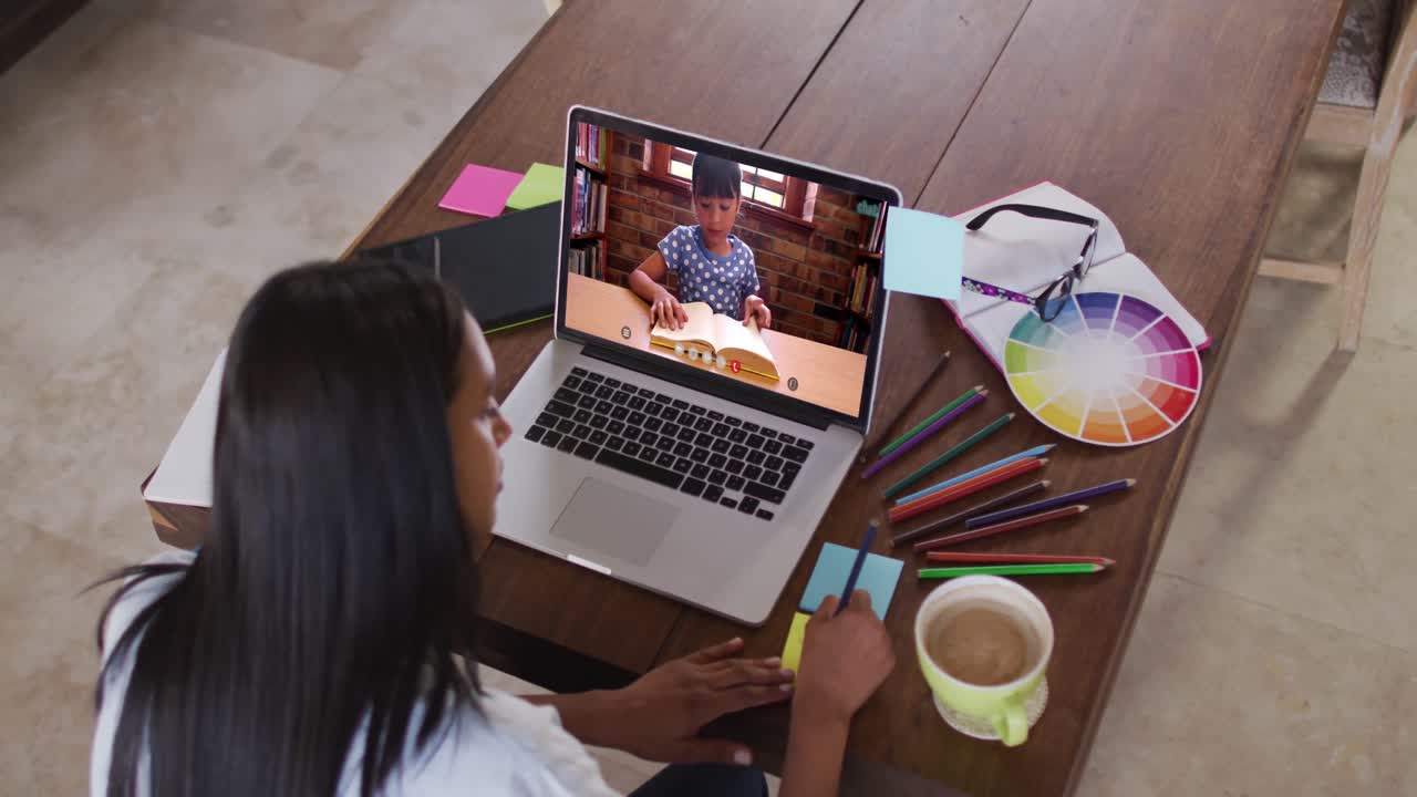 Maestra caucásica usando una computadora portátil en una videollamada con una alumna, tomando apuntes