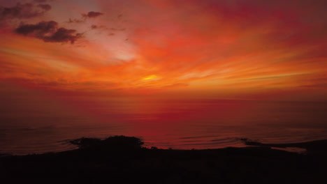 vista aérea cinematográfica de una vibrante puesta de sol roja sobre un océano tropical