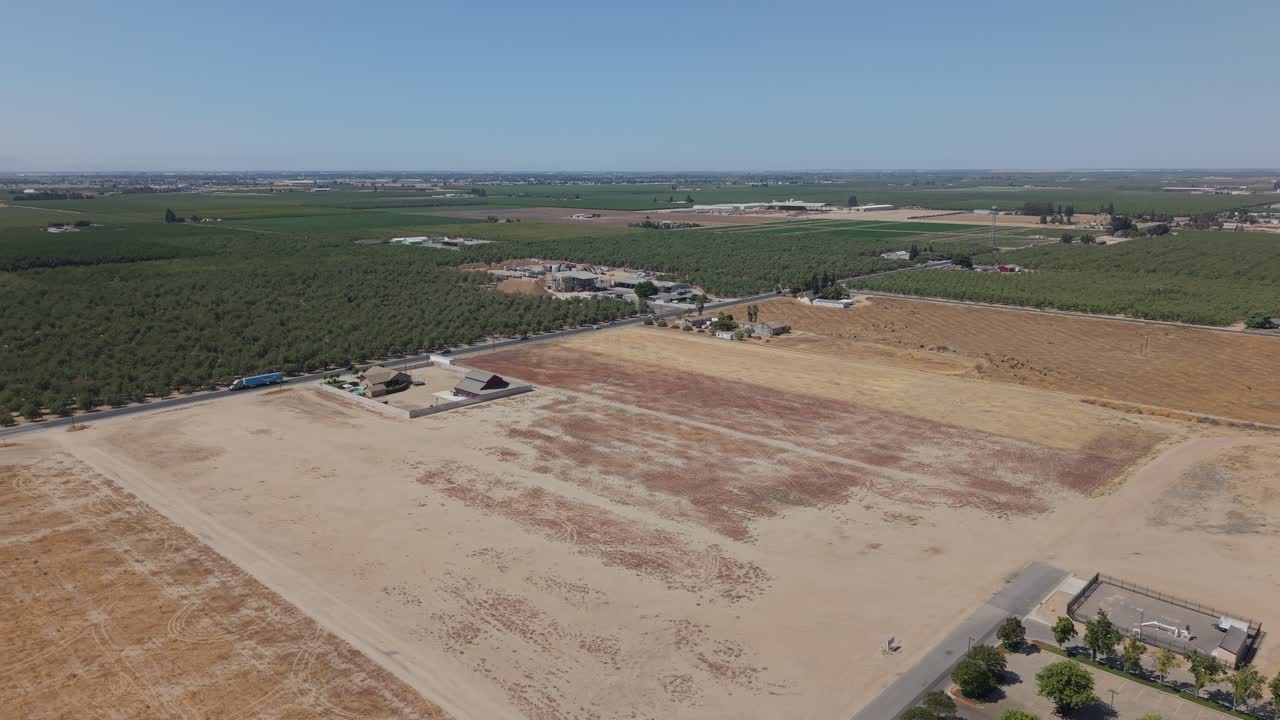 Aerial side shot showing farmland, road with traffic, houses, and open fields in Ripon California