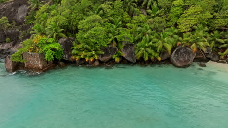 Aerial-view-of-small-exotic-beach-surrounded-by-green-lush-vegetation-in-the-Seychelles