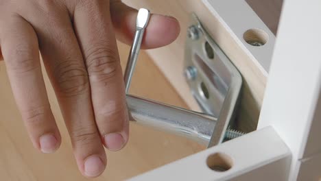 hand assembling white furniture with a metal bolt