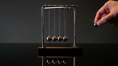 hand pulling ball of newton cradle