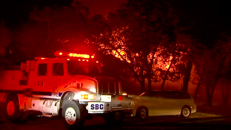 un camión de bomberos se sienta en la calle mientras el incendio navideño ruge en el fondo en goleta california