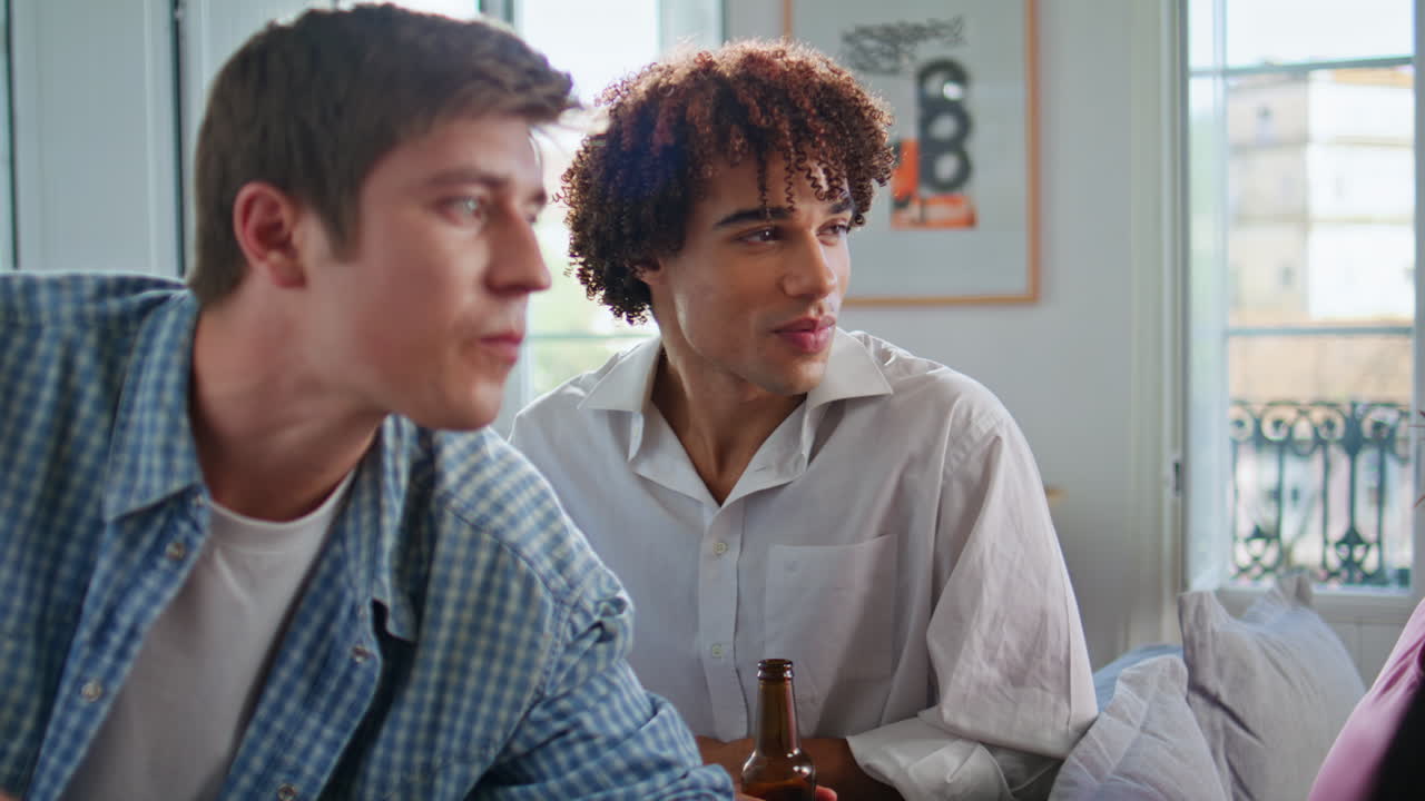 Excited guys watching football game supporting team together at home closeup