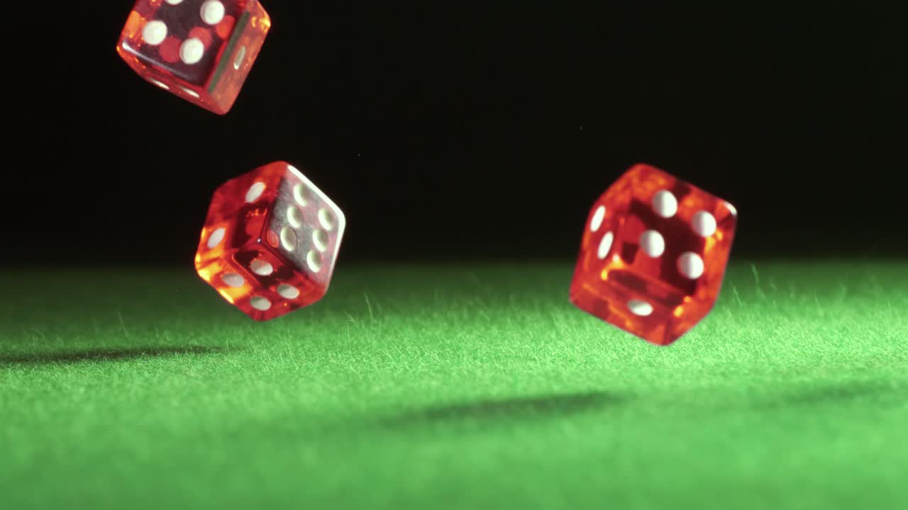 los dados rojos caen y rebotan en la mesa verde sobre un fondo oscuro. filmado con una cámara súper lenta de 1000 fps.