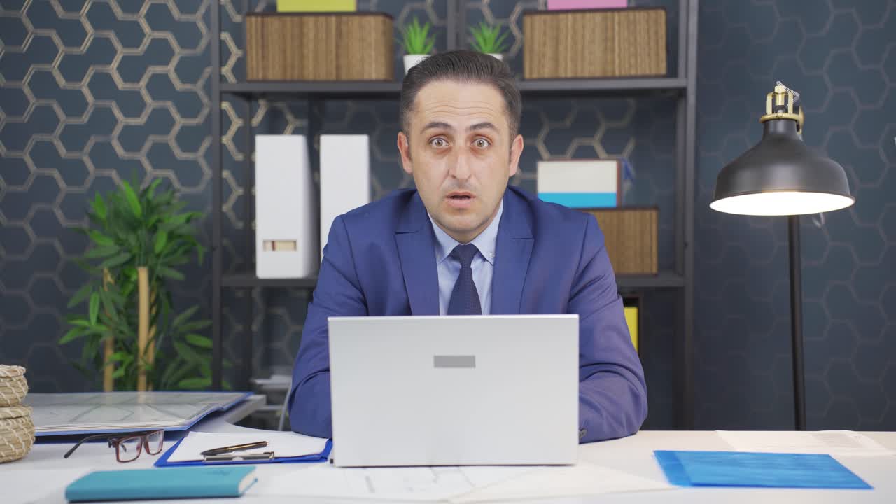 사업가는 놀라움과 놀라움으로 카메라를 쳐다보고 있습니다.