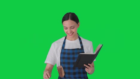 ama de casa india feliz haciendo comida del libro de recetas pantalla verde