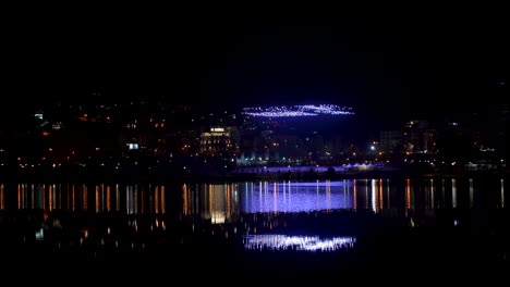 drones elevándose hacia el cielo nocturno sobre el paisaje urbano reflejado en el lago de agua para un hermoso espectáculo
