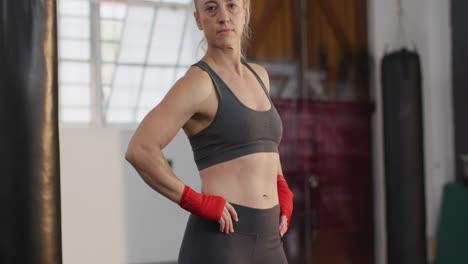 portrait of caucasian female boxer with hands on hips standing at the gym