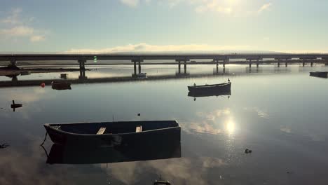 tranquil morning scene with boats moored on a calm lake, a bridge in the distance. peaceful landscape, nature, serenity concept.