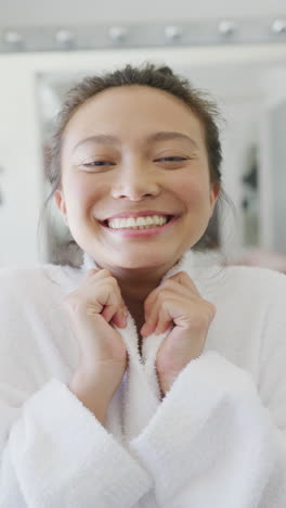 vertical video of portrait of happy asian woman smiling in bathroom, in slow motion