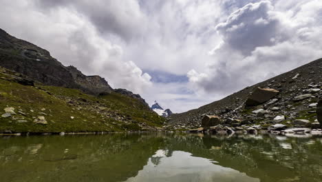 agua serena en el pequeño lago alpino con un cielo nublado en zermatt, suiza, europa durante el día - lapso de tiempo