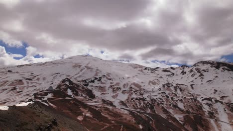 Schneebedeckte-Berge-Und-Wolken,-Die-Mit-Hoher-Geschwindigkeit-über-Den-Himmel-Ziehen