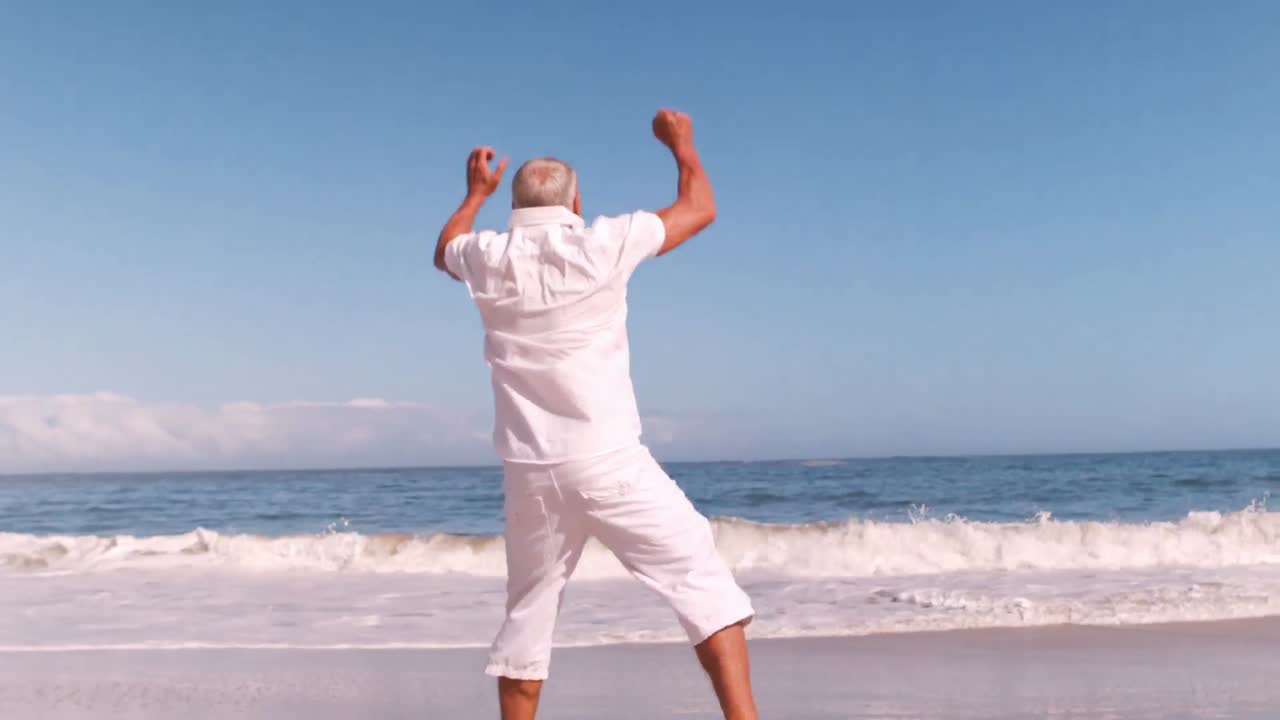 Uomo anziano che salta sulla spiaggia