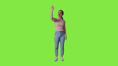 full length tudio shot of woman looking all around and interacting with vr environment against green screen