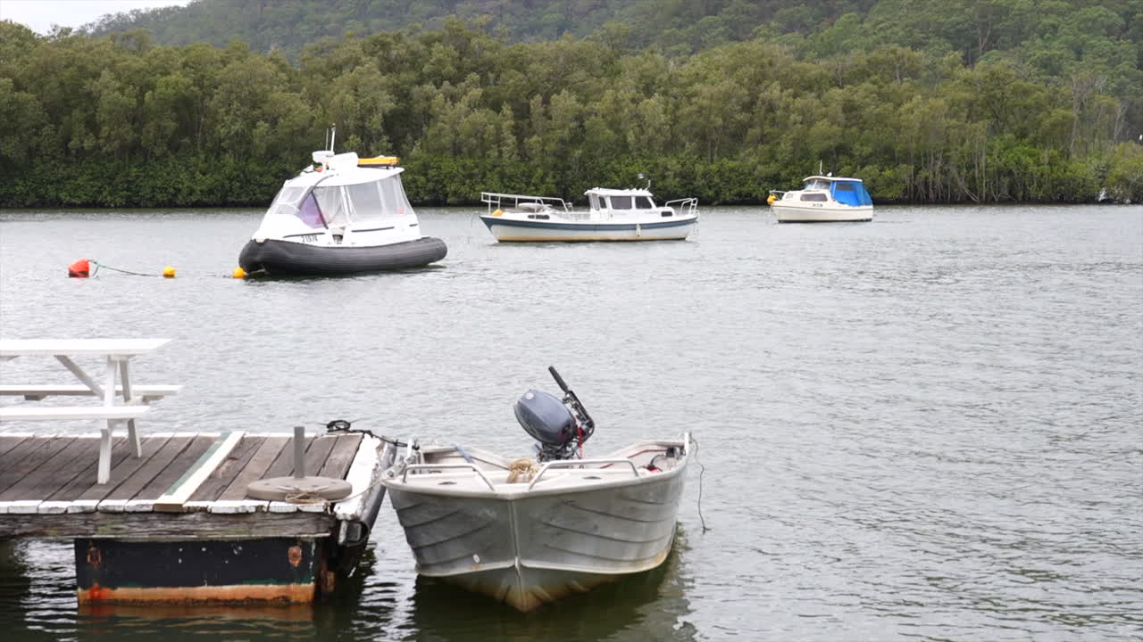 Boats and a tinny moored up on the Hawkesbury river in Spencer, NSW, Australia
