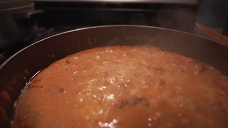 pushing in over a bubbling hot simmering pot of red tomato sauce