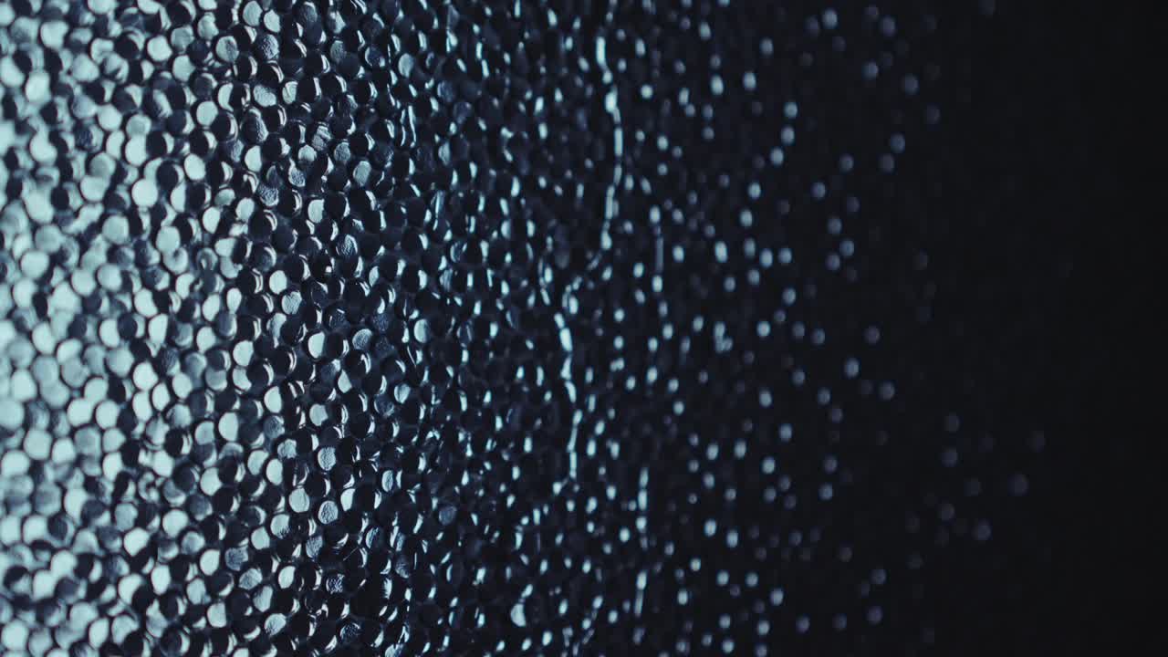 Water trickles onto moody turquoise textured glass window background