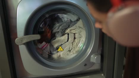 person watching clothes wash in a public laundry