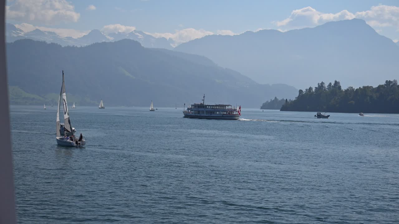 Ferry flying the Swiss flag and sailboats on Lake Lucerne, Switzerland