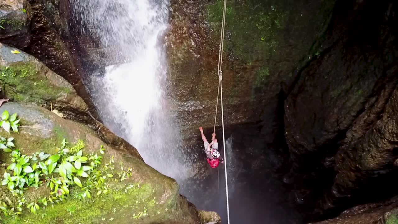 Man spelunking into a hole with cascade next to him in Puyo Ecuador
