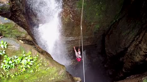 Man-spelunking-into-a-hole-with-cascade-next-to-him-in-Puyo-Ecuador