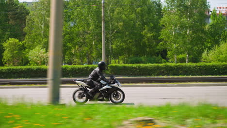 Skilled-rider-drives-powerful-bike-along-road-past-park