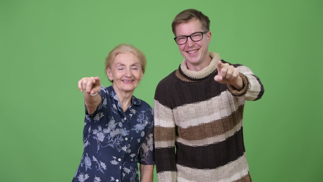 Happy grandmother and grandson pointing at camera together