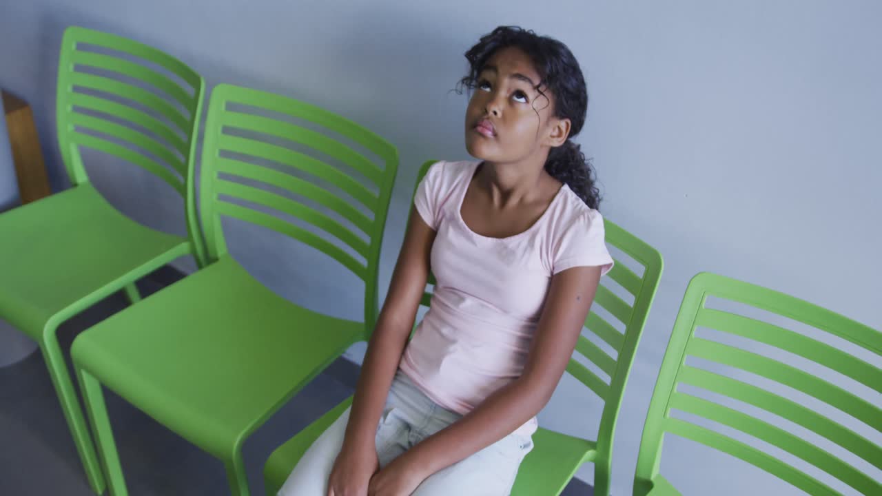 chica afroamericana con los brazos cruzados sentada en una silla en el hospital