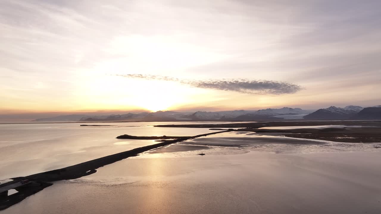 Aerial view of Hafnarnes, near Höfn in southeastern Iceland, showing the tranquil waters of Hornafjörður Lagoon and the distant Vatnajökull Glacier at sunrise.