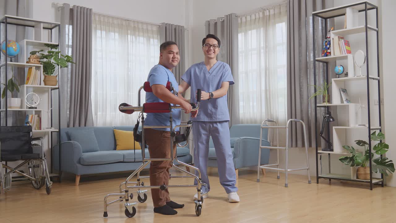 아시안 남성 간호사와 러를 입은 환자가 집에서 물리 치료를 하는 동안 카메라에 서서 미소 짓고 있는 전체 몸의 측면 시각