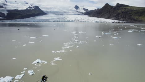 A-glacier-melting-into-a-serene-lake-in-iceland-on-a-sunny-day,-aerial-view