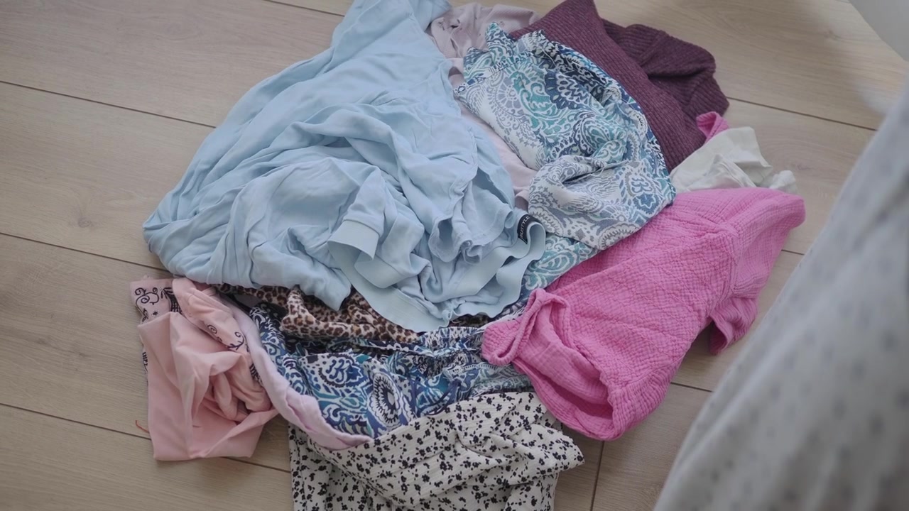 Person Dropping Light Blue Clothing onto a Pile of Laundry