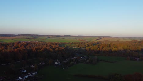 autumn aerial view over english countryside with small village and fields and forests in golden hour light - drone shot in dorset uk 4k
