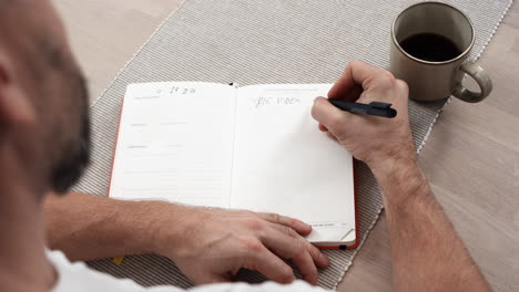 man writing in journal at home - high angle