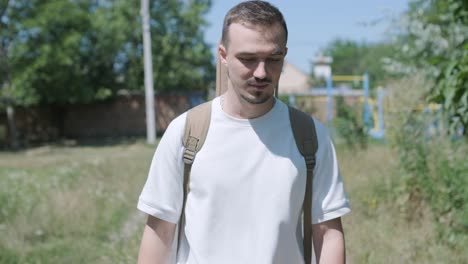 young man walking with guitar on street near forest