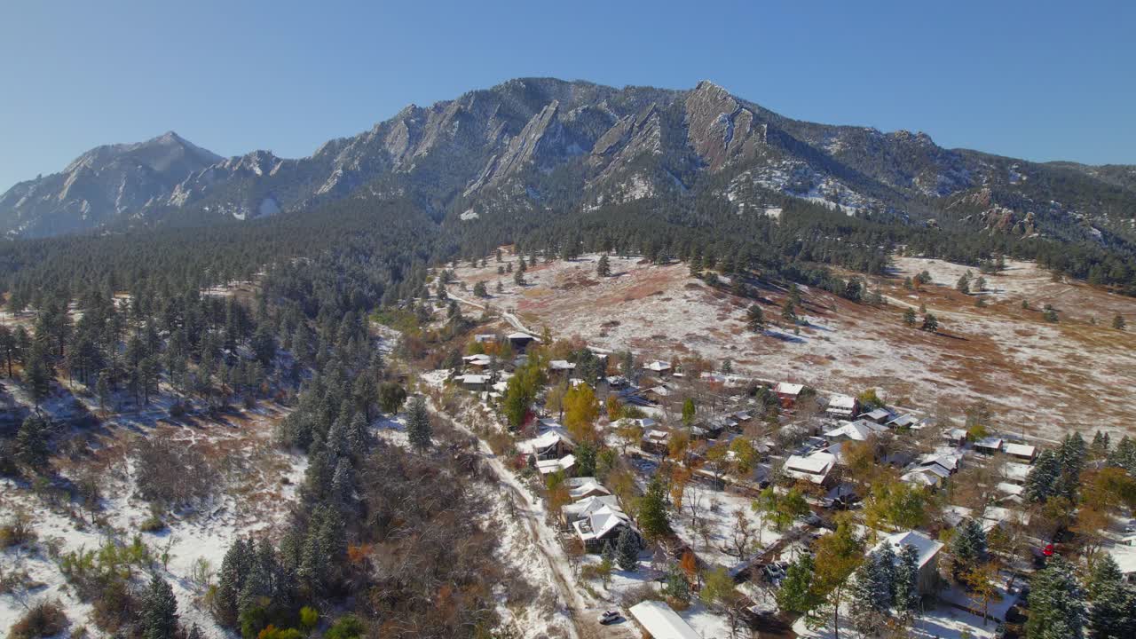 drone aéreo que se eleva y revela el paisaje de flatirons cubierto de nieve con colores de otoño en un día despejado