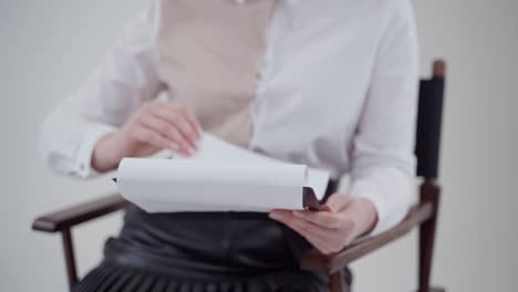 folder in woman's hands. young secretary in blouse sitting in the chair and flipping papers. close-up. slow motion.