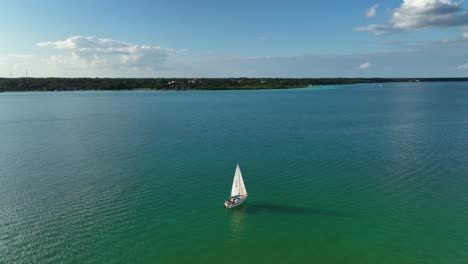 Vista-Aérea-Alrededor-De-Un-Barco-De-Vela-En-La-Laguna-Bacalar,-Soleada-Quintana-Roo,-México---órbita,-Disparo-De-Drones