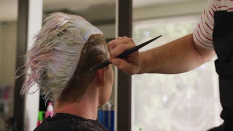 Rear-view-woman-having-her-hair-styled-by-a-hairdresser