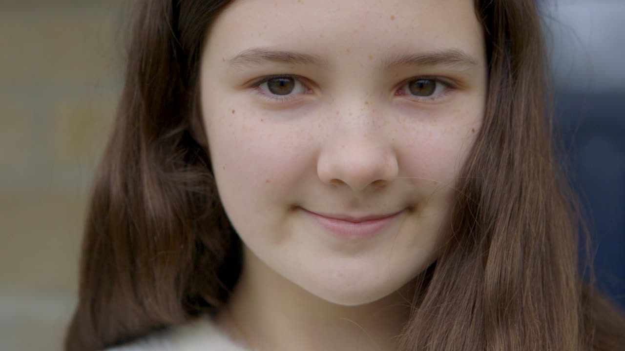 cerca de una linda chica con bonitos ojos marrones sonriendo dulcemente a la cámara