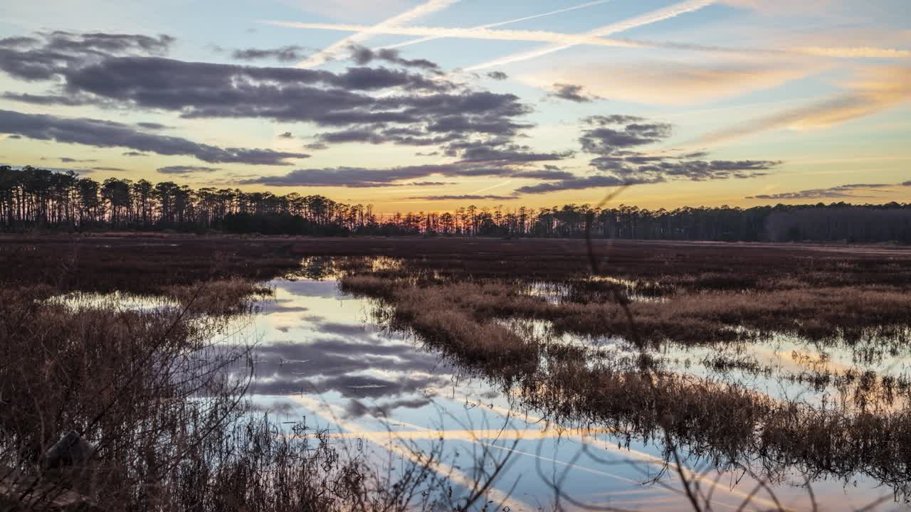 Time lapse over swampland as clouds roll in reflecting in the water