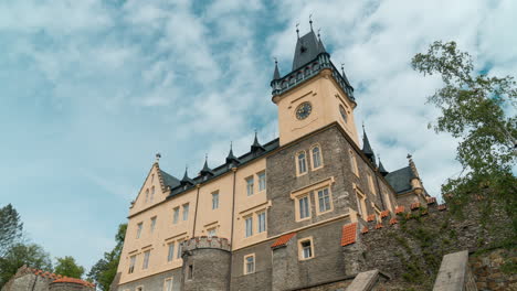 renaissance-palace-standing-on-a-wall-with-puffy-clouds-rushing-over-turquoise-sky,-low-angle-time-lapse