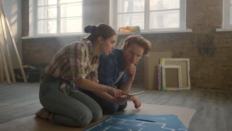 una joven familia discutiendo un proyecto de diseño en el interior. una pareja planeando la renovación de su casa.