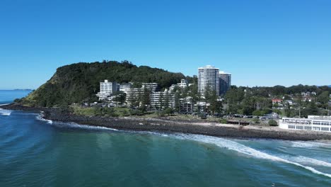 Surfer-Genießen-Den-Weltberühmten-Burleigh-Heads-Surf-Break-Mit-Der-Berühmten-Landzunge-Und-Der-Gemeinde,-Die-Sich-über-Ihnen-Erheben