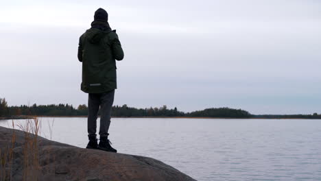 man-outdoors-exploring-by-the-Baltic-Sea-looks-out-with-binoculars