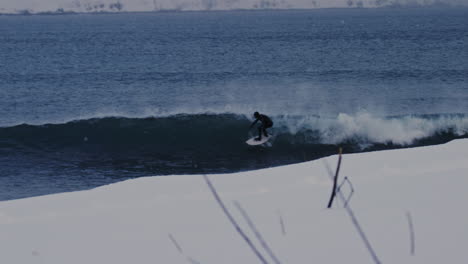 surfer carving arctic waves near icelandic coastline under overcast winter skies, slow motion tracking