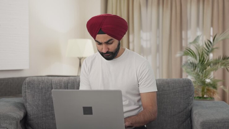 hombre indio sikh tenso usando una computadora portátil