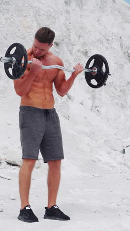 exercise for biceps in nature. a man in shorts comes up and raises the bar. vertical video