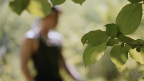 warrior bends head to tie headband while blurred in background, green leaves swaying gently in breeze, dappled sunlight filtering through dense forest canopy on summer trek giving beautiful view